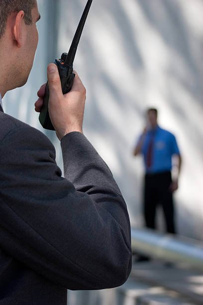 security guard talking with walkie talkie in his hand ( blured background)